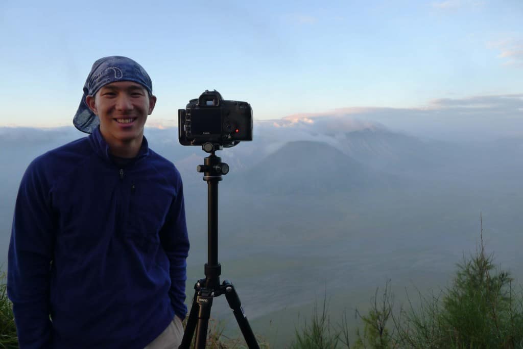wearing the original buff headwear with tripod and camera and landscape behind