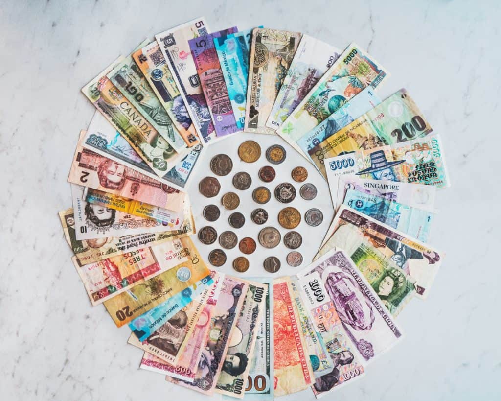 a circle of currency from around the world including bills and coins on marble counter