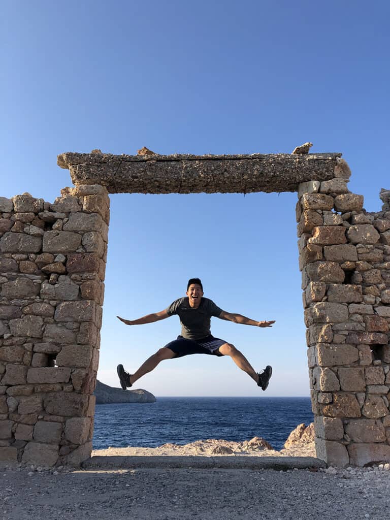jumping in a brick door opening with sea behind in milos greece